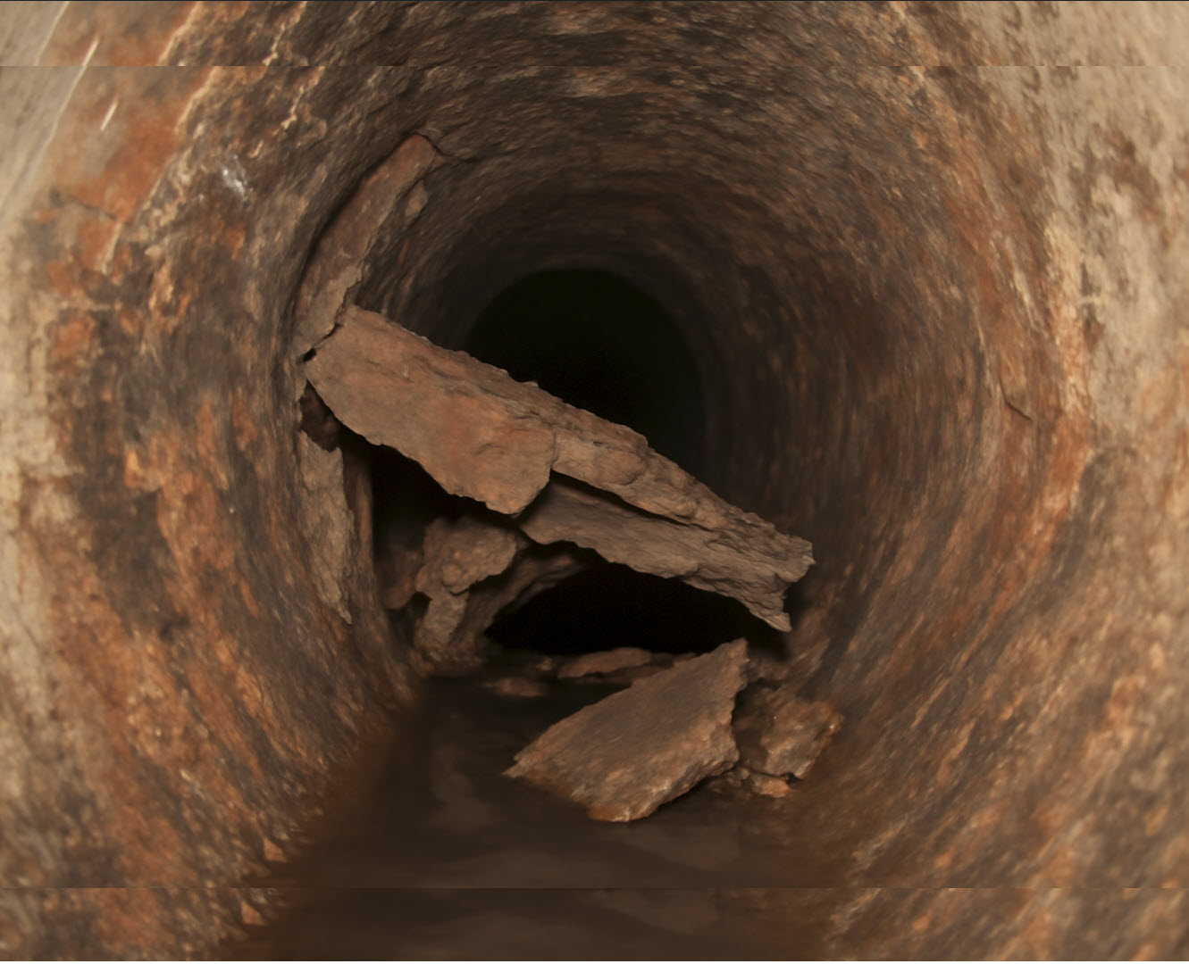 2025-07-08_16-36-42 This image shows a severely deteriorated clay or cast-iron sewer pipe, at this 1980s home in Tomball home inspection